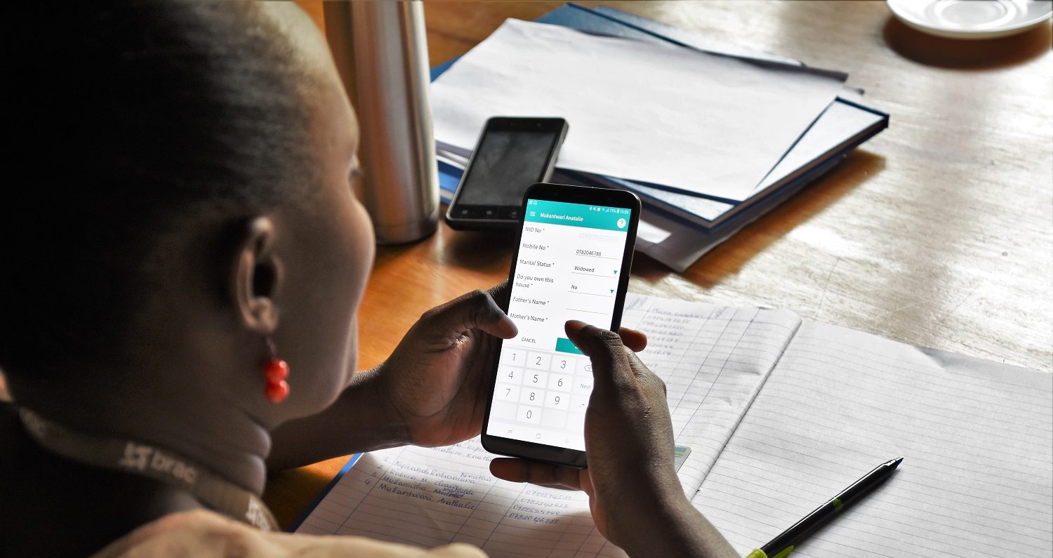 Women in Rwanda use a digital app on their phone to access their finances.